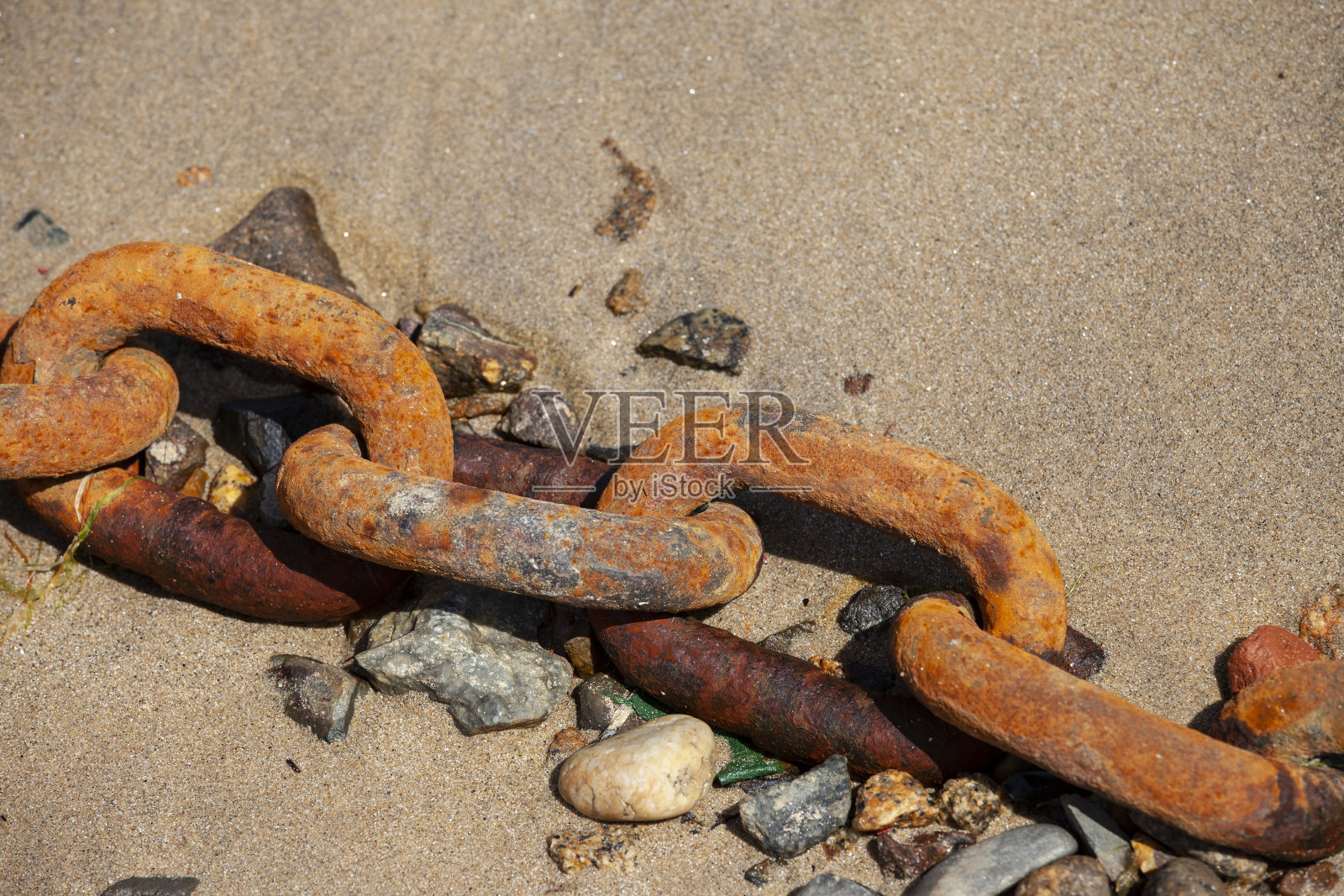 生锈的铁链断了,丢在沙子里。照片摄影图片