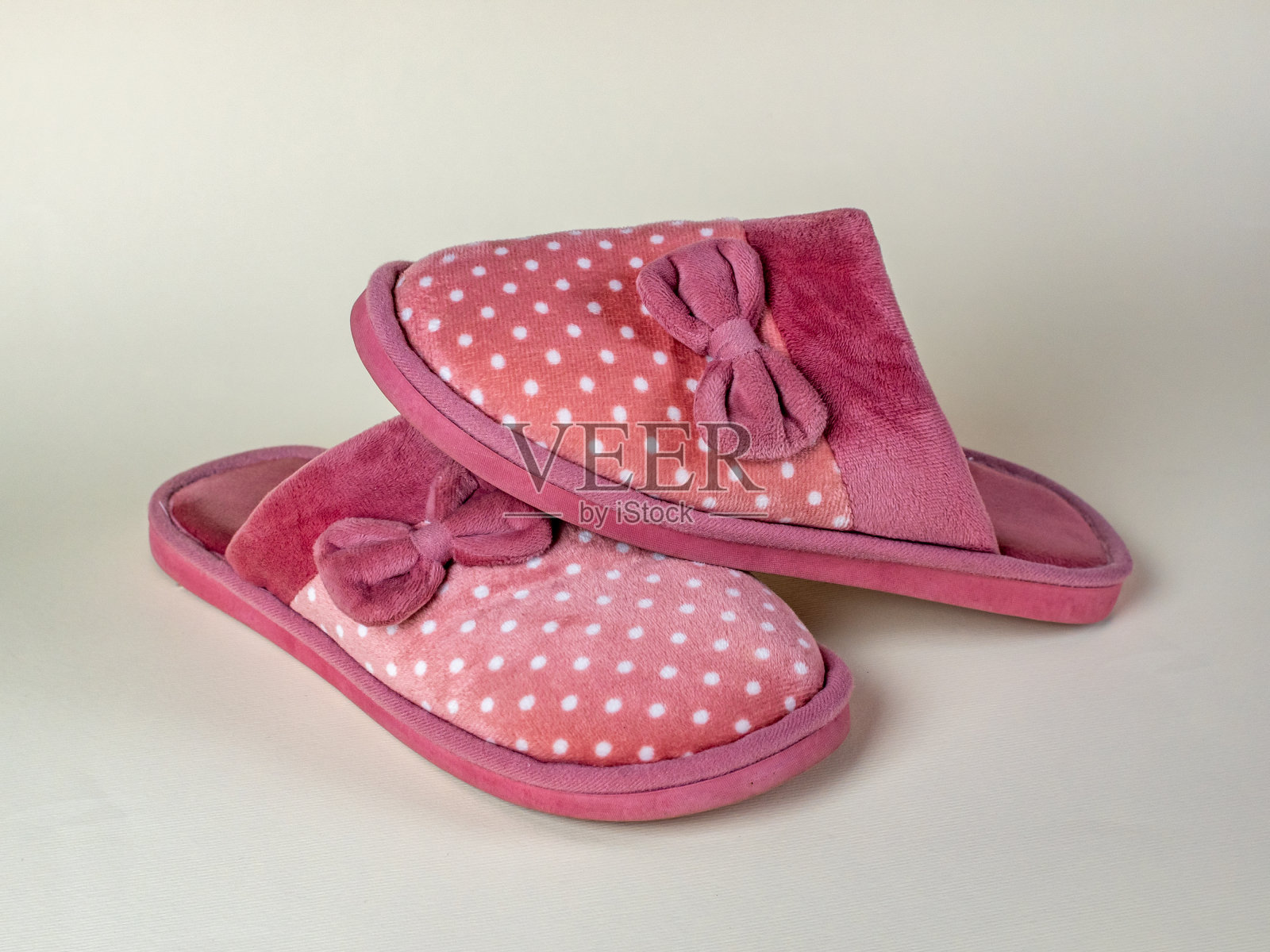 女式拖鞋,漂亮的粉色图案,白色圆点和蝴蝶结。一双女式拖鞋。现代室内鞋,适合在房子里走动,柔软,温暖,舒适照片摄影图片
