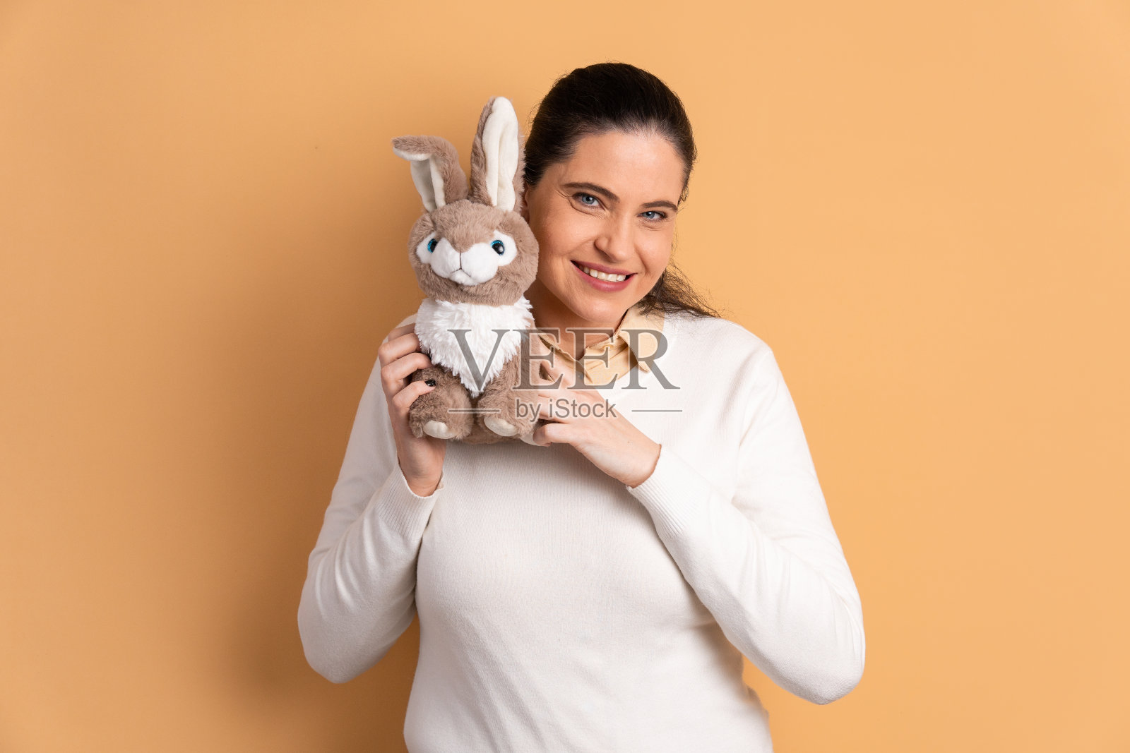 快乐成熟的女人复活节兔子米色。节日,复活节,庆祝概念。照片摄影图片