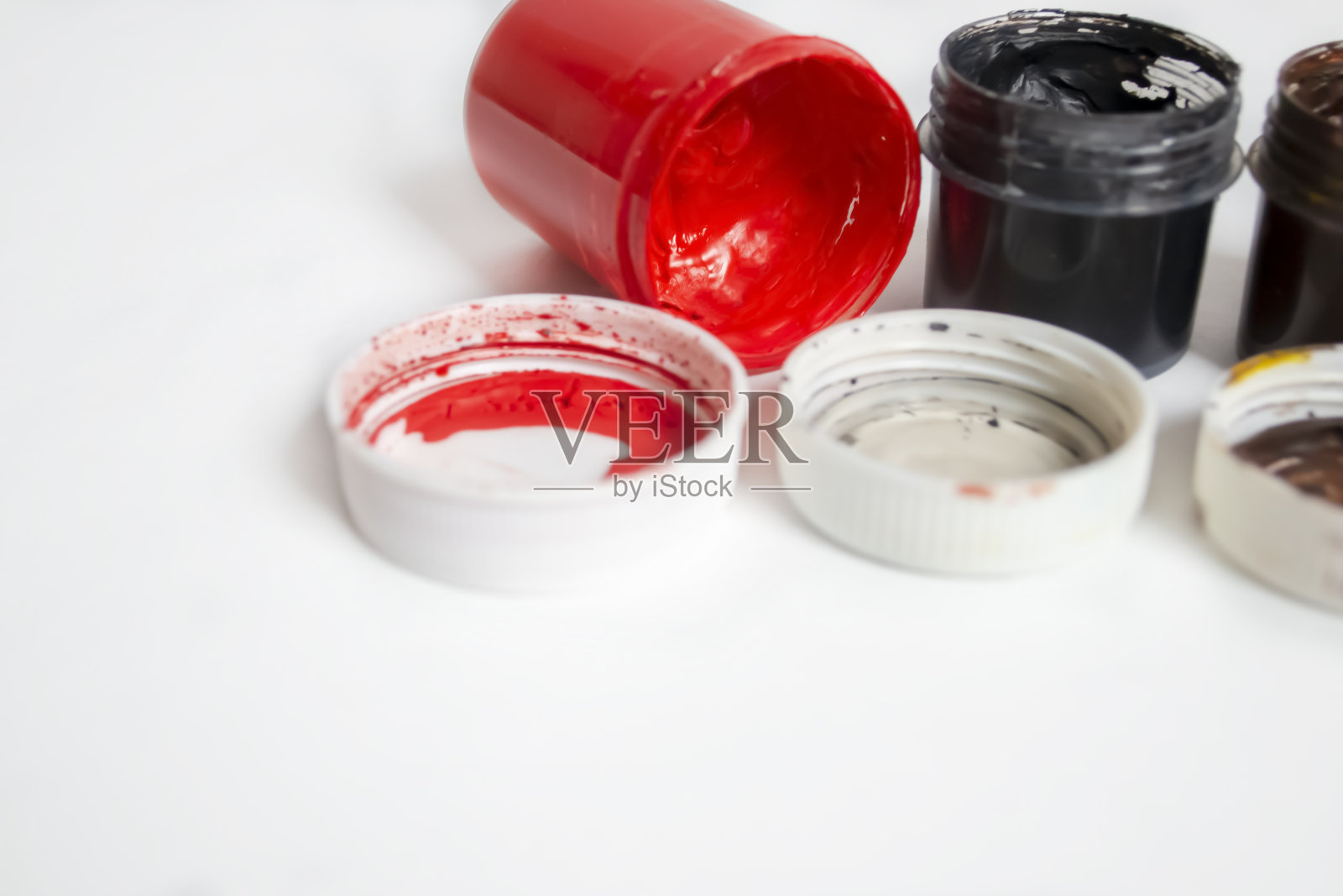 黑色旁边是红色水彩画。桌上有彩色颜料。白色背景上红黑水彩的罐子。照片摄影图片