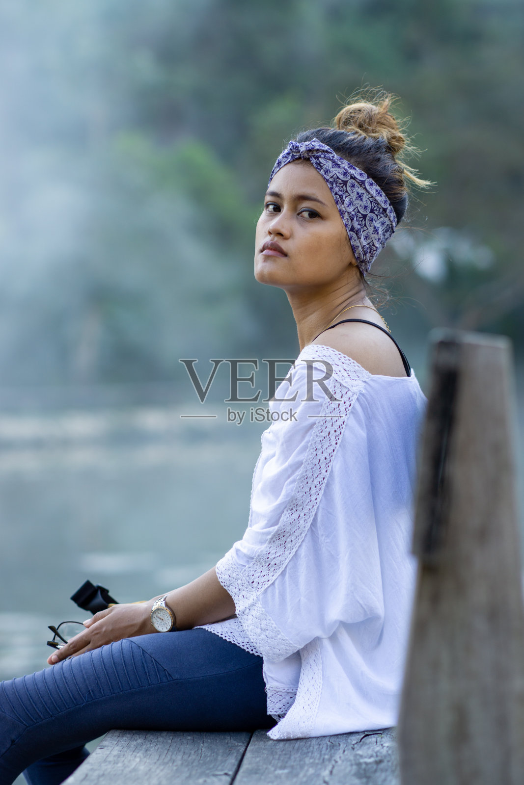 一位年轻美丽的东南亚模特戴着大手帕坐在木桥上照片摄影图片