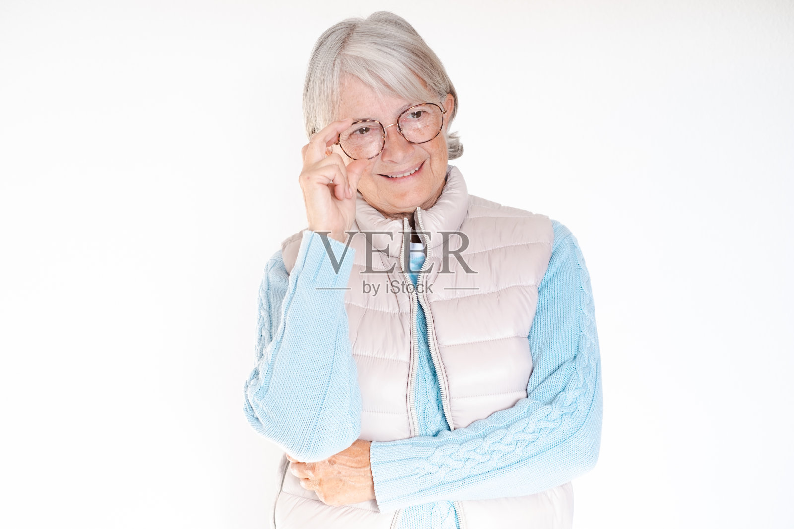 近距离拍摄白发苍苍的高龄女性,用手摸眼镜,看起来自信而微笑,具有运动优雅的风格,外表迷人照片摄影图片