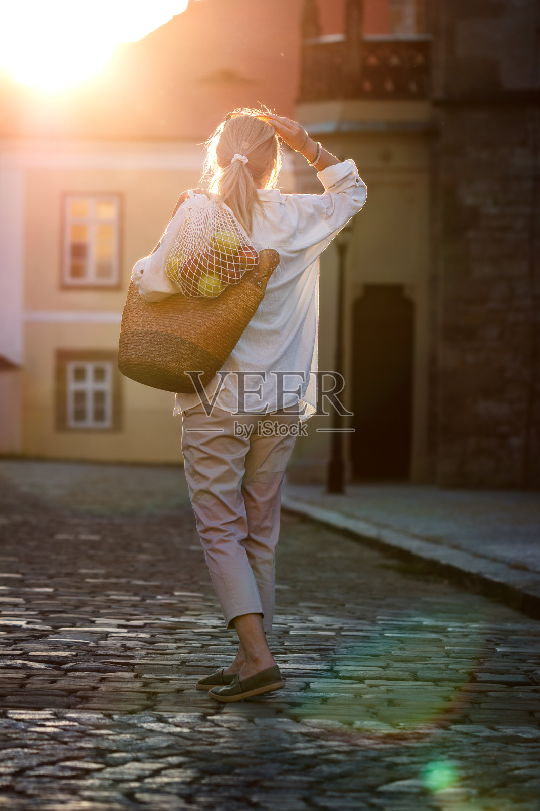 女子带着环保袋和网袋走在城市街道上照片摄影图片