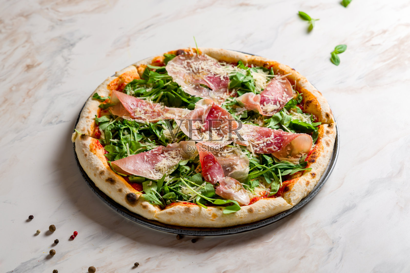 披萨配帕尔玛火腿和芝麻菜放在白色大理石桌上照片摄影图片