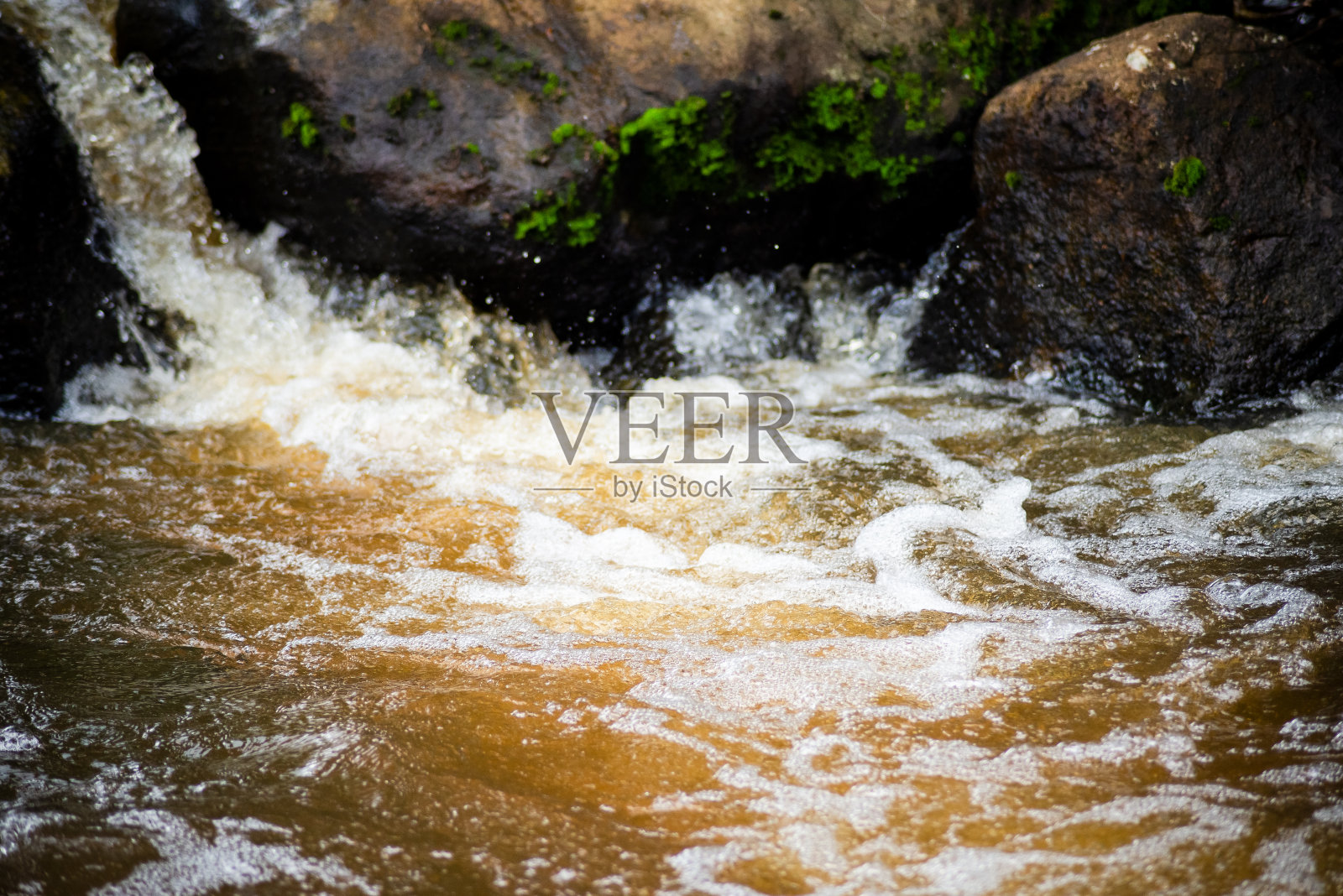 河水从岩石间快速流过。照片摄影图片