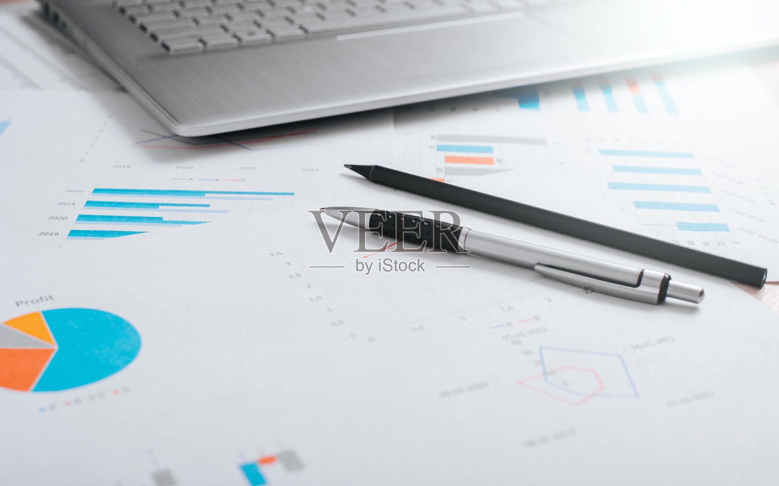 会计和财务概念。特写的钢笔,铅笔,笔记本电脑和商业文件在工作场所。低角度视角,选择性聚焦照片摄影图片