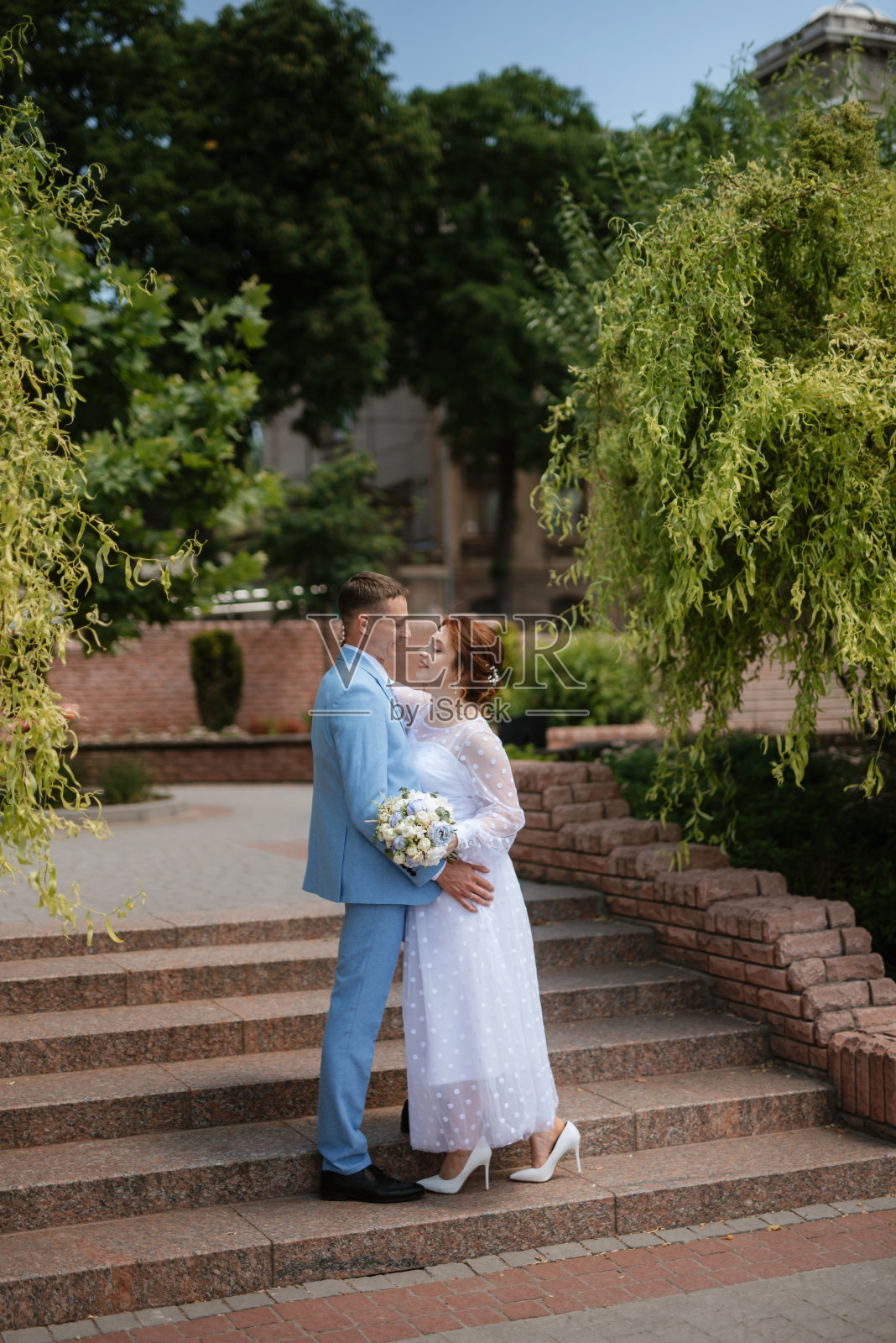 新娘身穿浅色婚纱,新郎身穿蓝色西装照片摄影图片