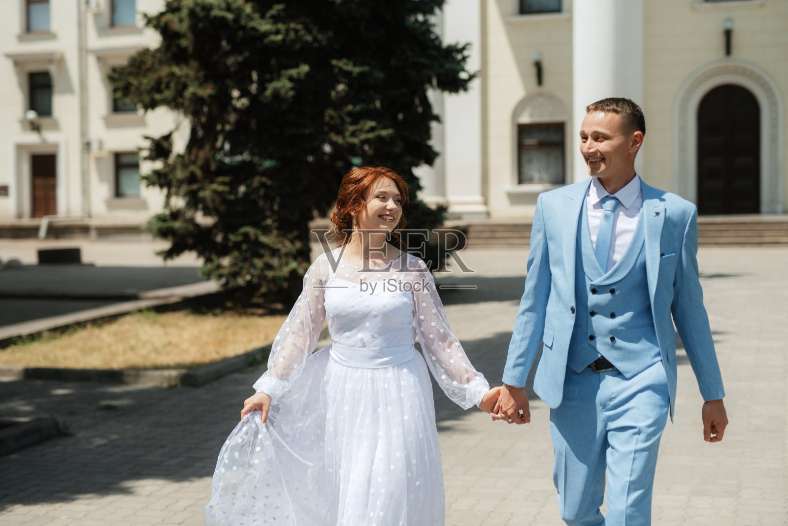 新娘身穿浅色婚纱,新郎身穿蓝色西装照片摄影图片