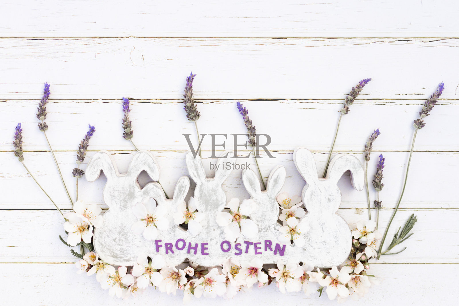 柔软平坦的白色和灰色木制复古复活节兔子形状与薰衣草和杏仁花和德语字母Frohe Ostern什么意思复活节快乐的白色木制背景照片摄影图片