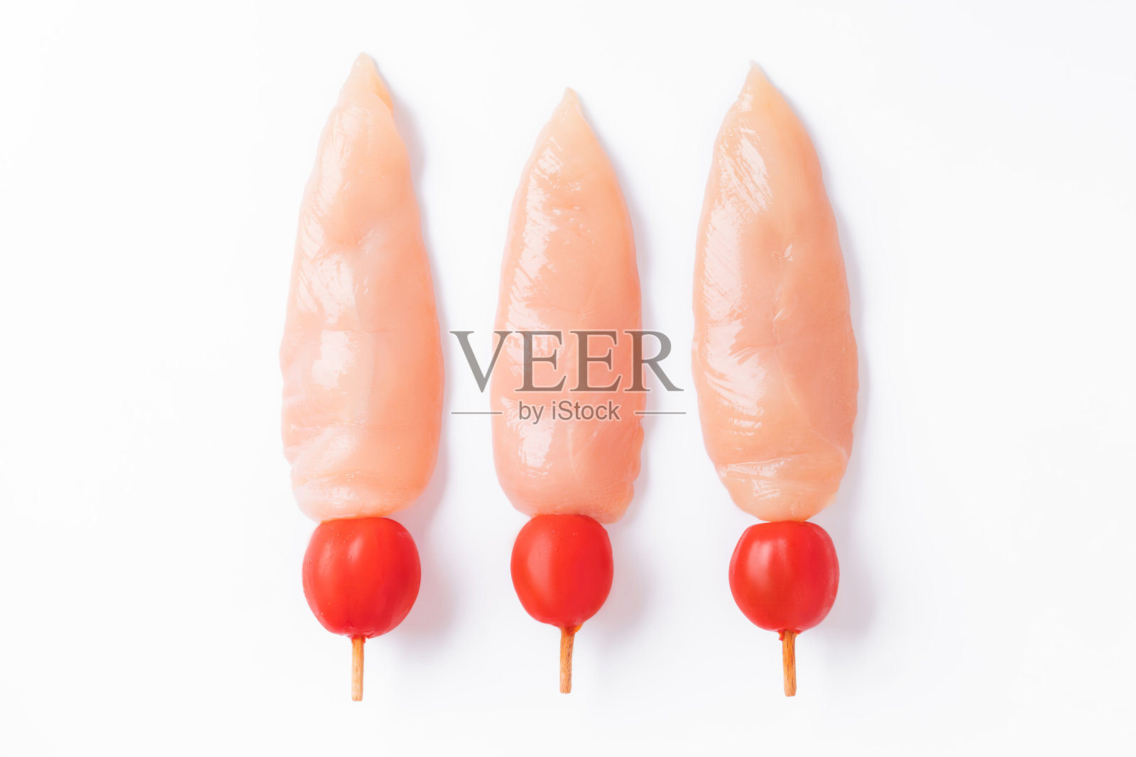 生鸡肉串上白色背景的西红柿。生的未煮熟的鸡肉,串在白色背景的烤串上。生鸡肉串。生肉和蔬菜串。特写。俯视图照片摄影图片