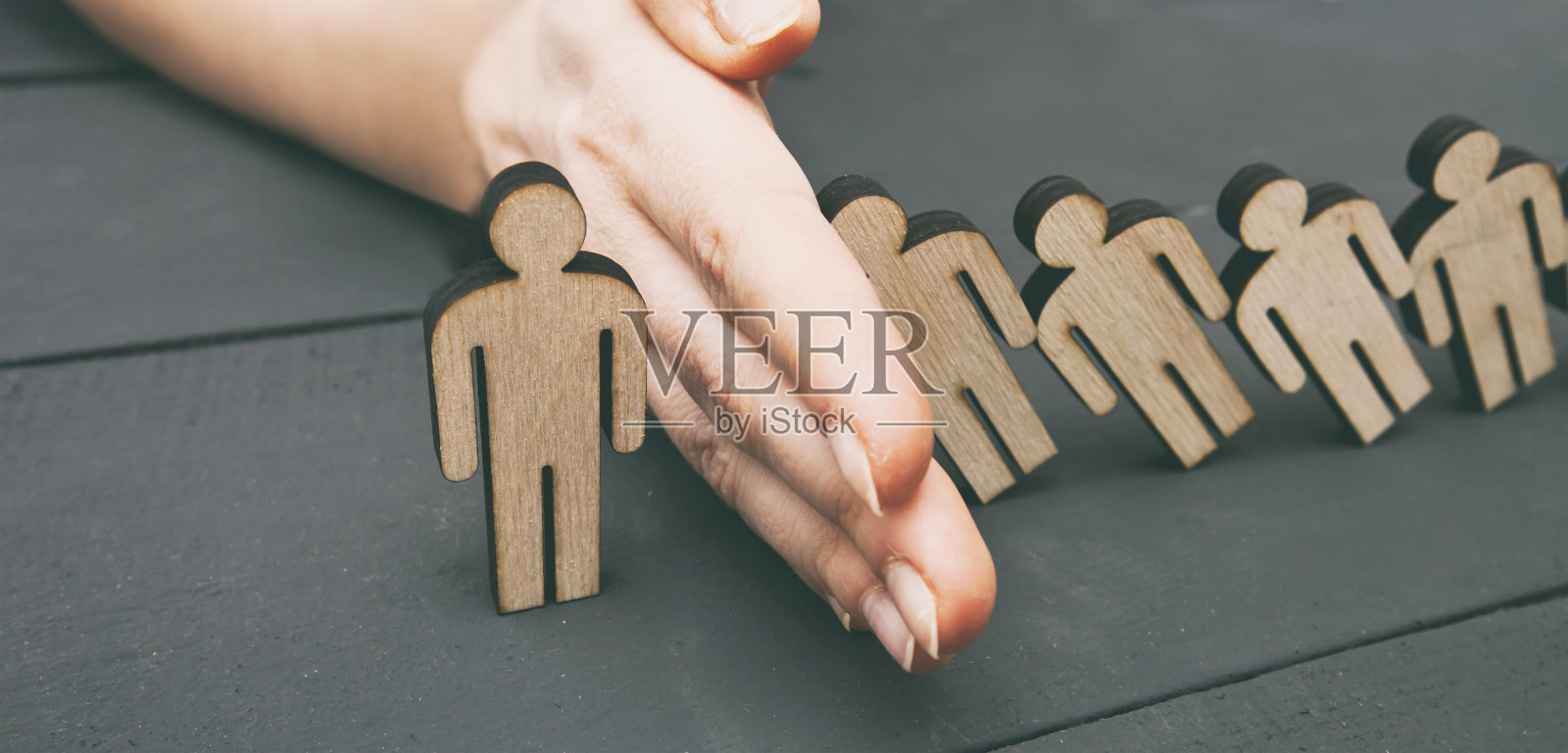 五个木头人倒在另一个人身上,但人的手阻止了它。照片摄影图片