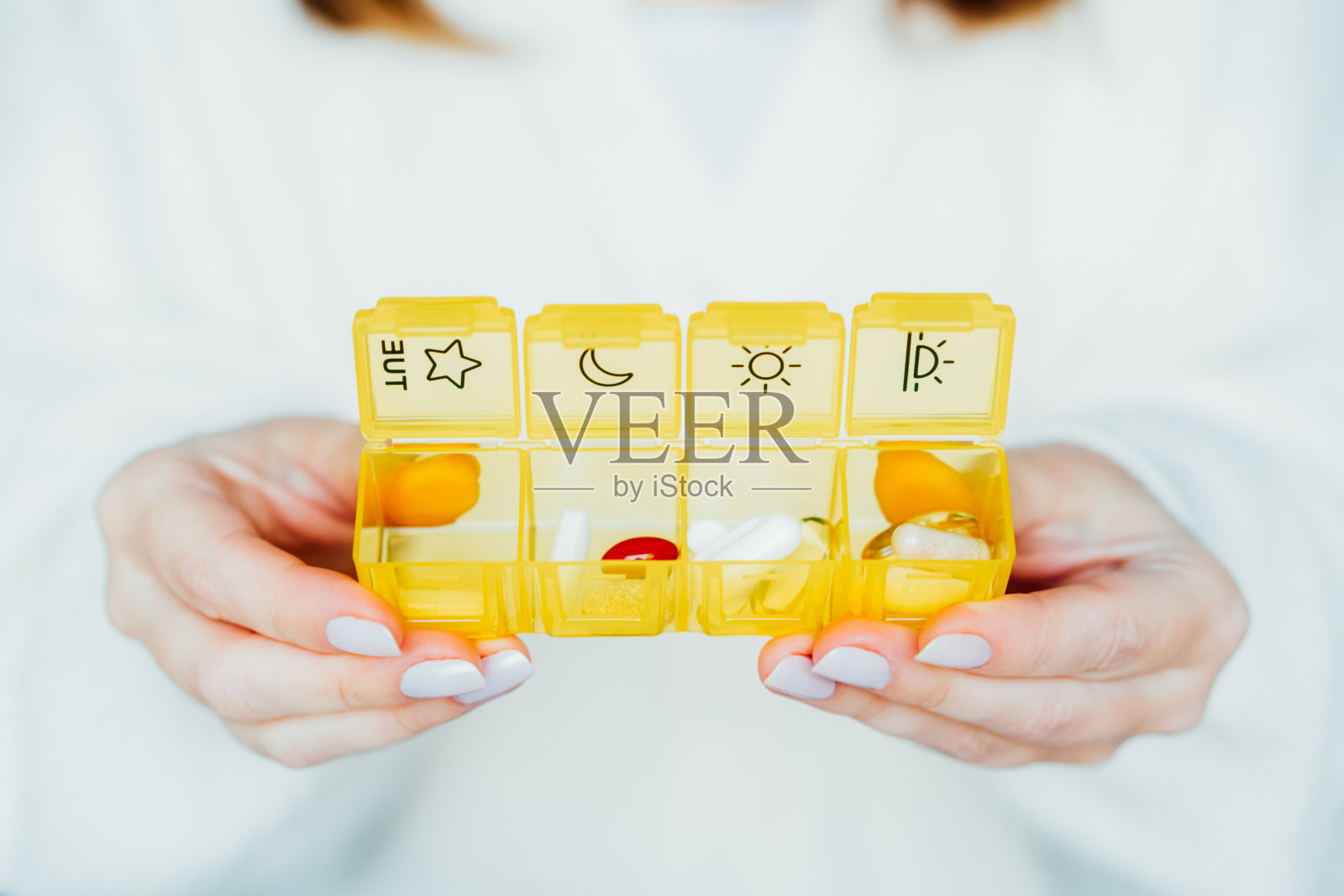 女性手握打开的每日药丸收纳箱。每日服用药物抗氧化饮食维生素补充剂美容皮肤头发保健药物生物黑客概念。有选择性的重点。照片摄影图片