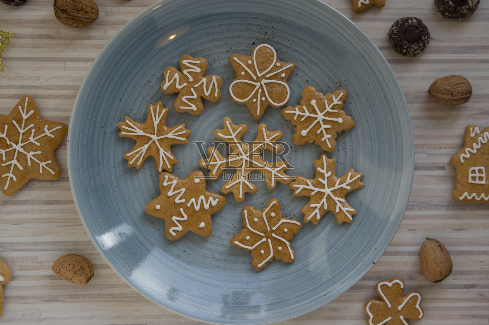 彩绘的传统圣诞姜饼摆放在白色木桌上的蓝色盘子上,各种圣诞形状照片摄影图片