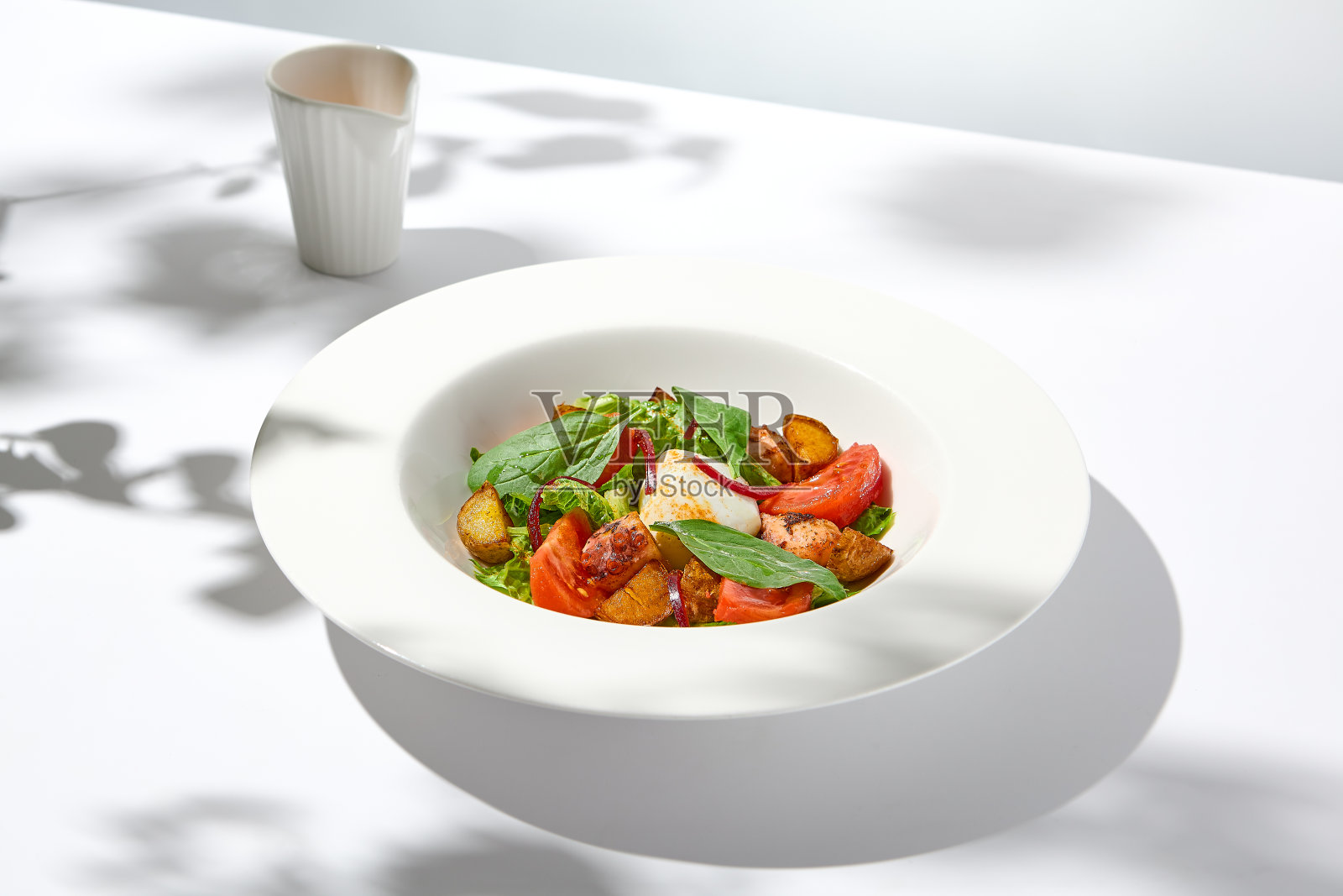 沙拉章鱼,烤土豆和荷包蛋在白色的桌子上硬阴影。海鲜沙拉配蔬菜和土豆夏季菜单餐厅。现代风格的章鱼鸡蛋沙拉。照片摄影图片