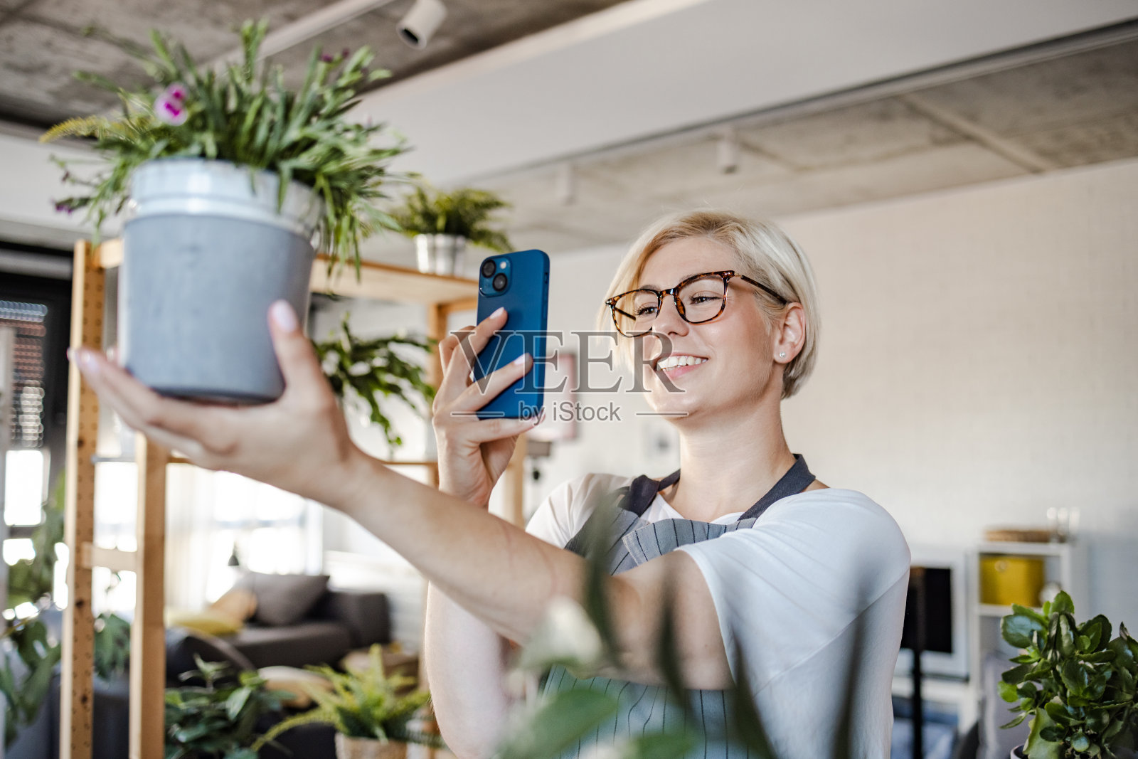 年轻女子正在给室内植物拍照照片摄影图片