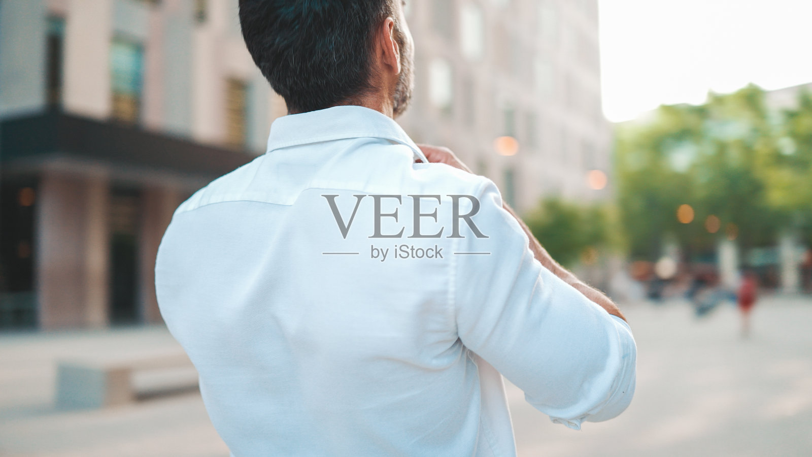 成熟的商人,留着整齐的胡子,整了整白衬衫,走在现代都市的街道上。成功的人轻松自在,享受生活照片摄影图片