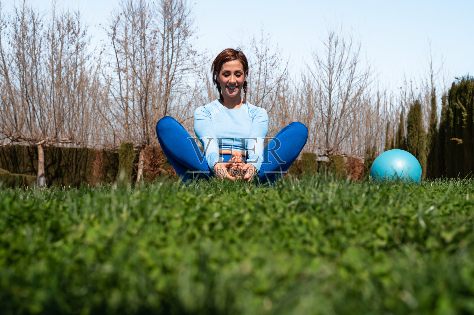 迷人的运动女人在日光下在公园里做拉伸柔韧性和放松练习照片摄影图片
