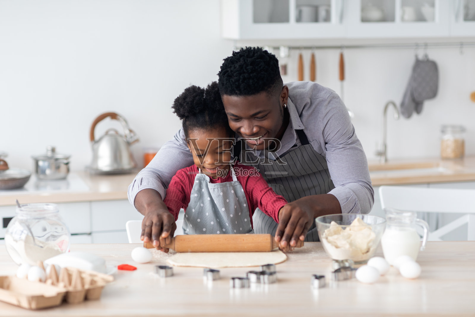 可爱的黑人父亲和小女儿一起做饼干,擀面团照片摄影图片