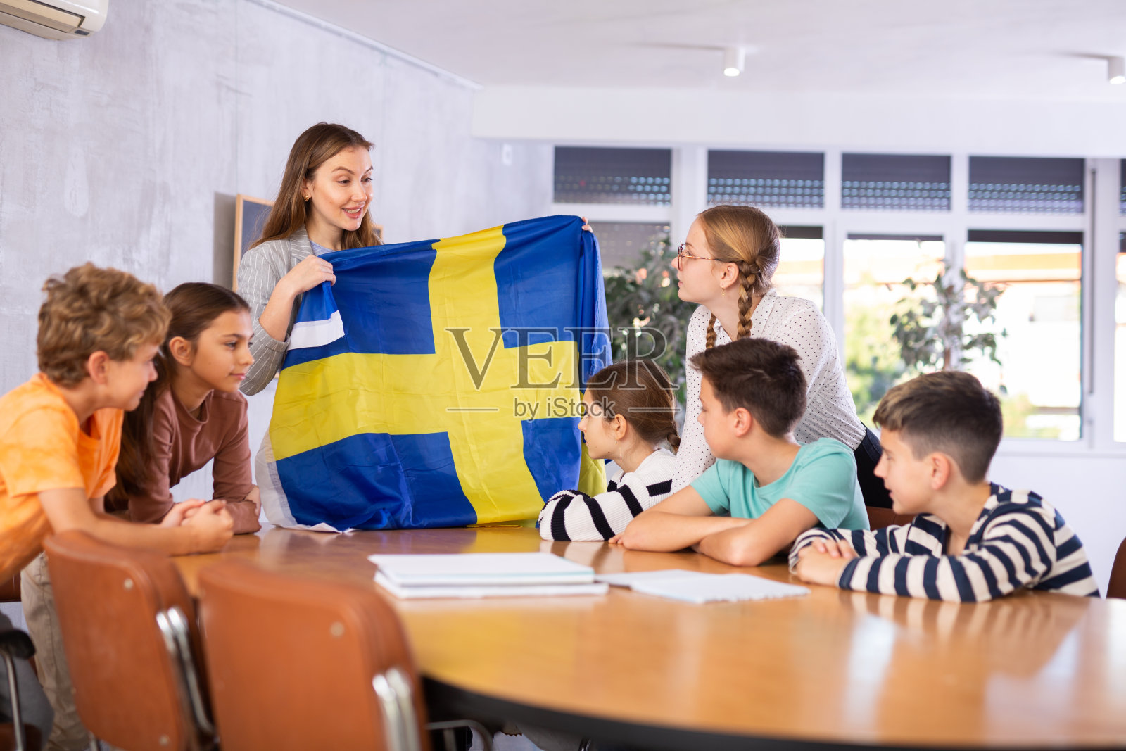 女老师举着国旗向同学们介绍瑞典照片摄影图片