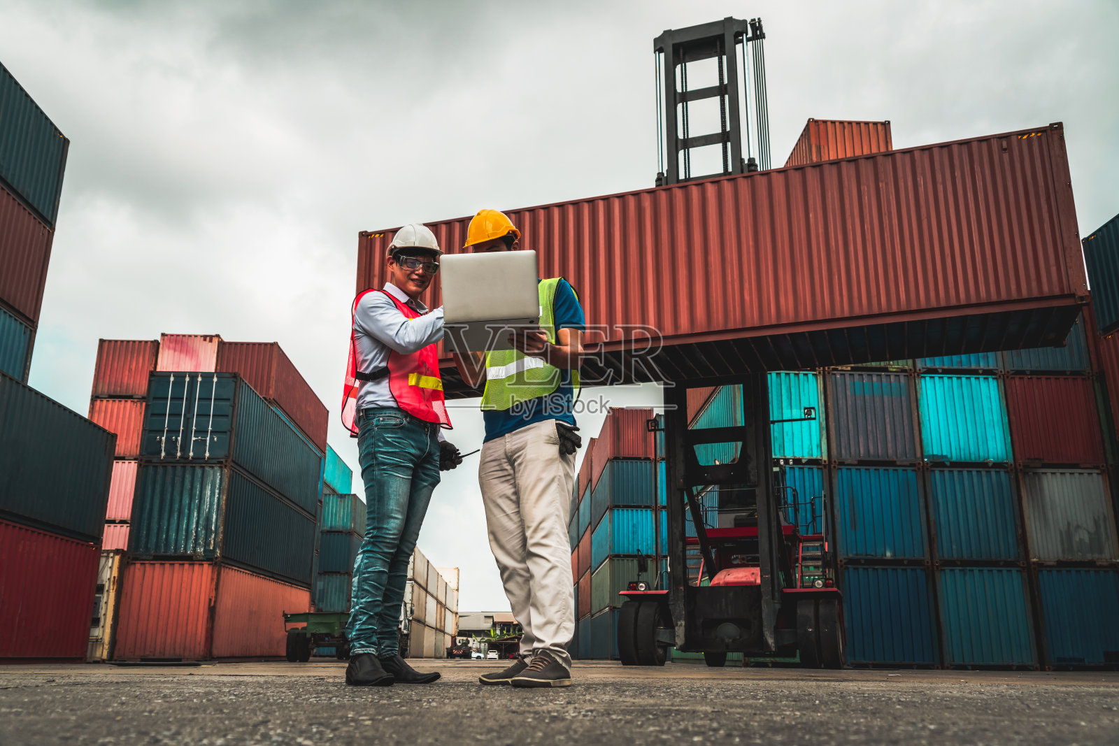 产业工人在海外集装箱堆场与同事一起工作。物流供应链管理与国际货物出口概念。照片摄影图片