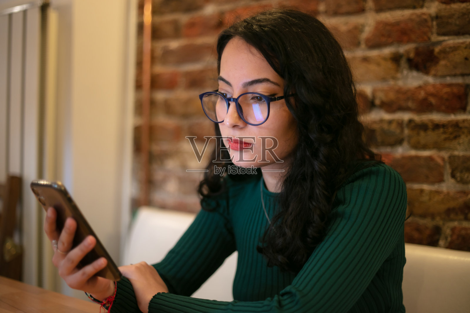 年轻的黑发女孩在发短信。照片摄影图片