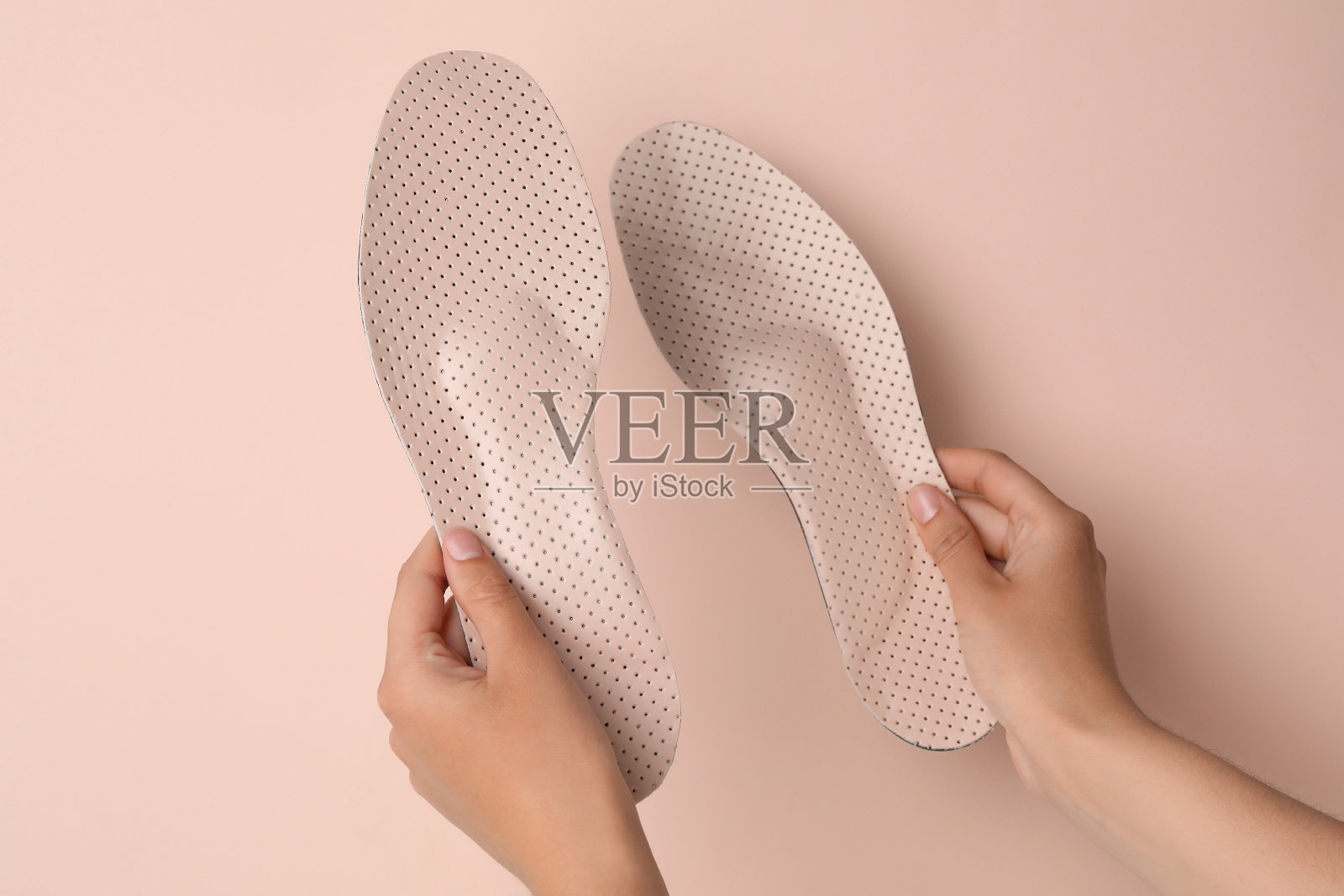 女子抱着矫形鞋垫在粉红色的背景,特写照片摄影图片