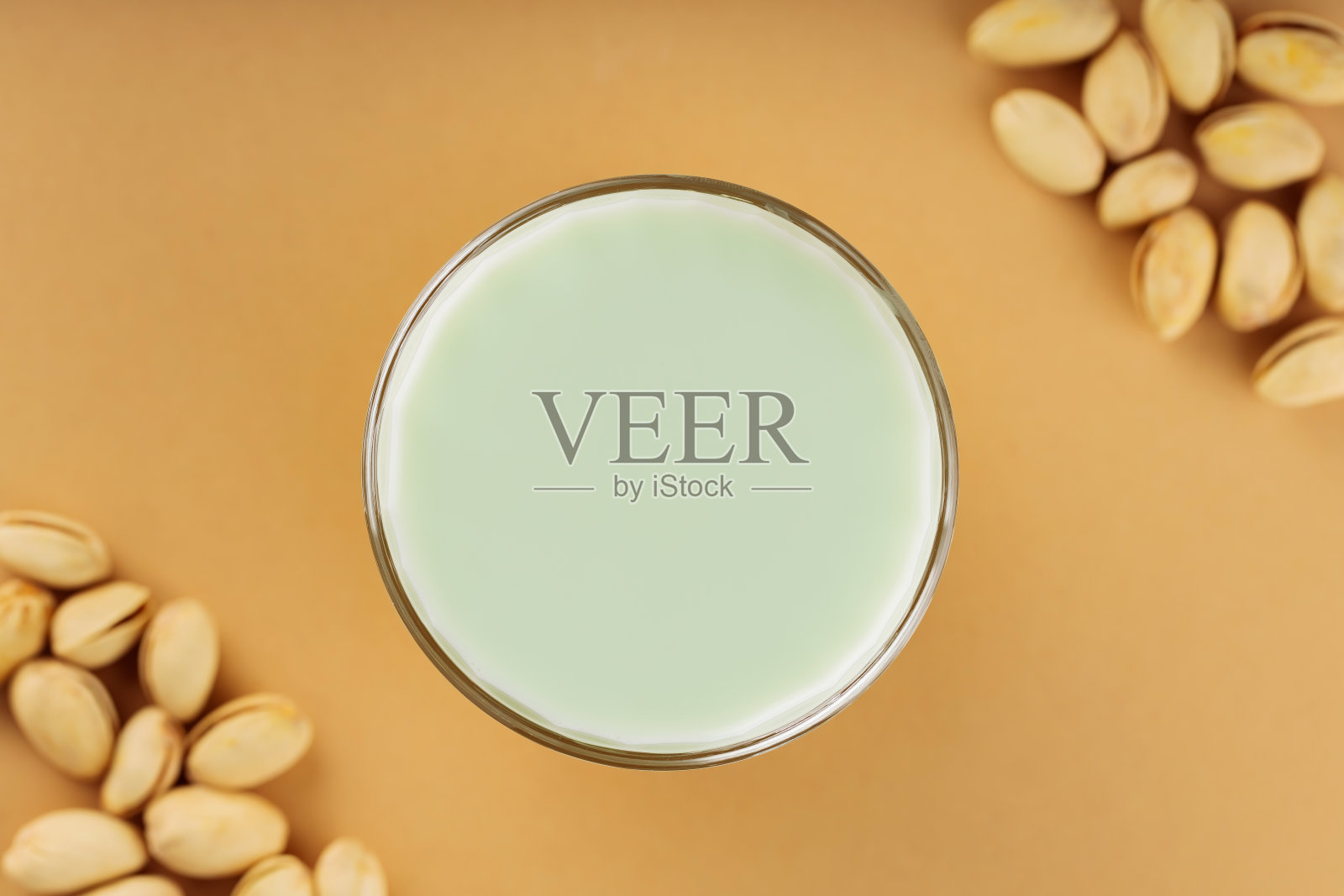 米色背景上的一杯开心果牛奶。素食植物绿色开心果牛奶。前视图。本空间照片摄影图片