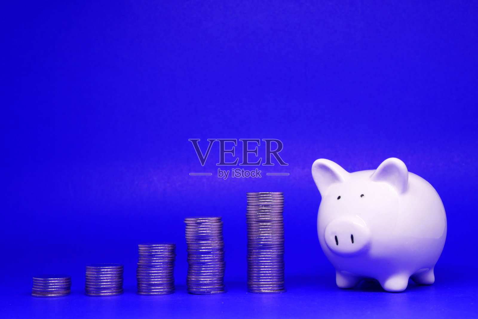 基金,投资,储蓄概念:白色的存钱罐和硬币在蓝色背景与文本信息复制空间-蓝色图案的银行和金融,贷款和利益的概念照片摄影图片