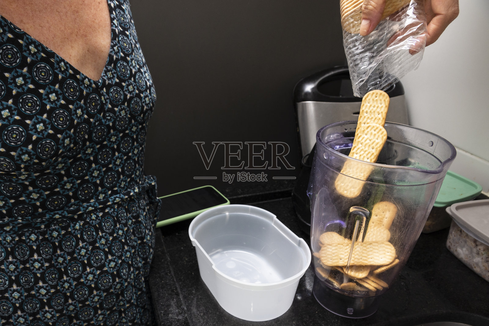 年轻女子把食材放进搅拌机。家里的美食。照片摄影图片