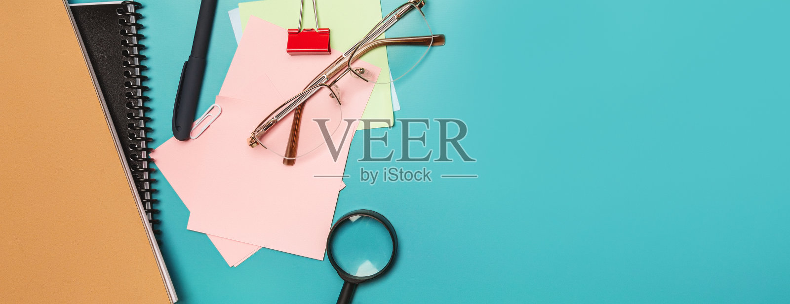 创意平面桌面照片。办公办公桌的顶视图文具,眼镜,笔记本电脑和复制空间在柔和的绿色背景。前视图。照片摄影图片