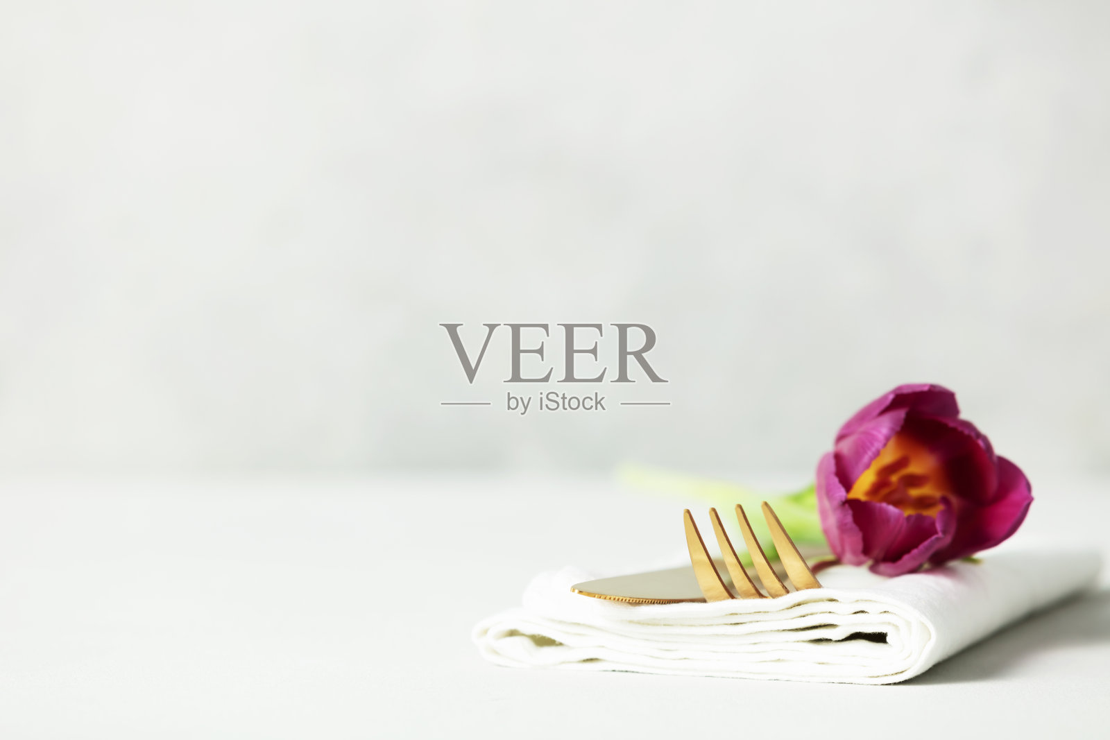 浅灰色的桌子上有金色餐具和美丽的花朵,还有文字空间照片摄影图片