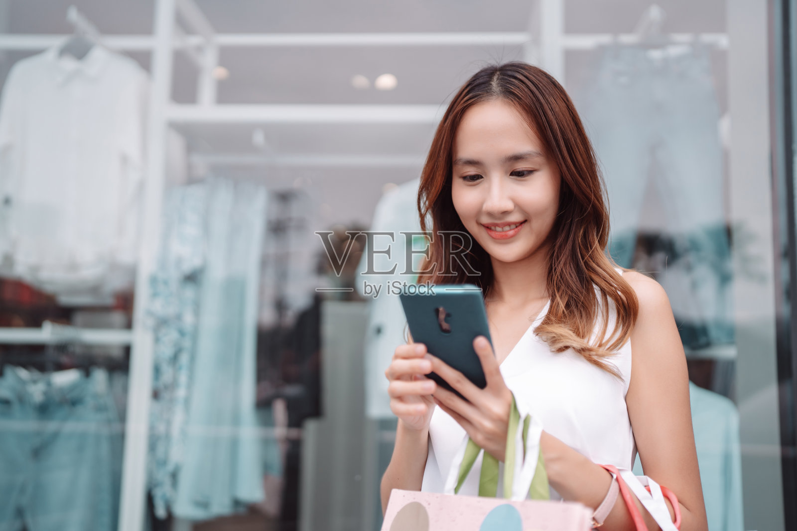 美丽的亚洲女性女子女孩拿着购物袋,散步享受微笑,在百货商场的橱窗外购物户外时尚的生活方式照片摄影图片