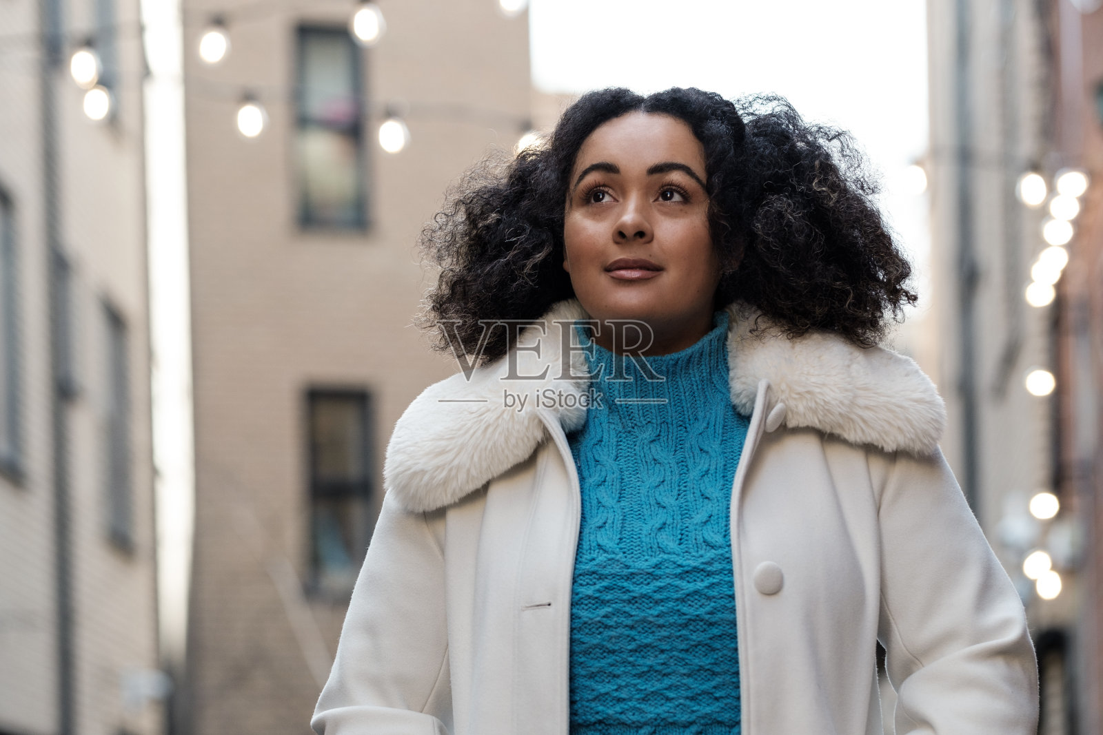 一位身材曲线优美的年轻女子站在伦敦一条狭窄的街道上。照片摄影图片