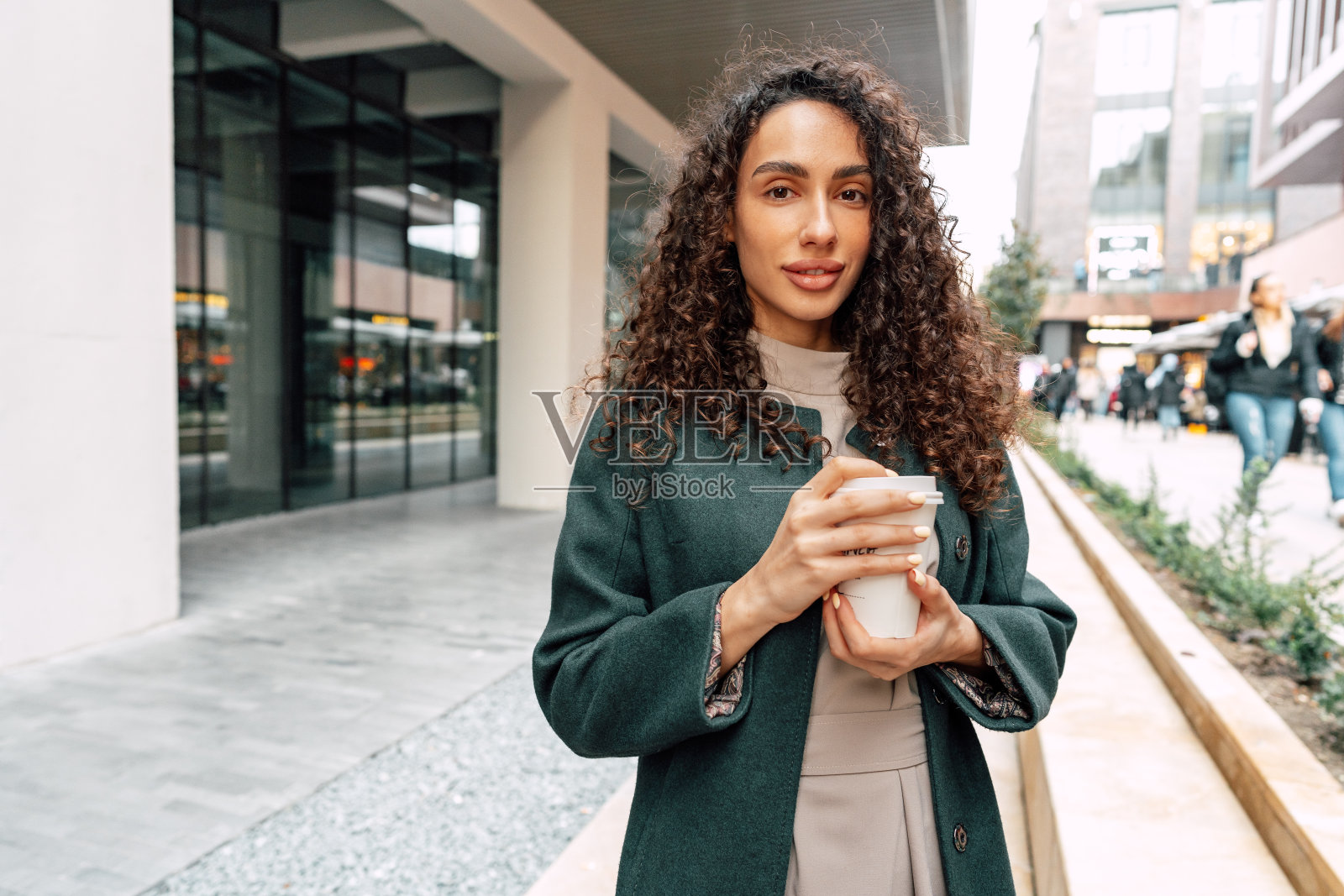 年轻开朗的女人拿着咖啡杯走在城市里照片摄影图片