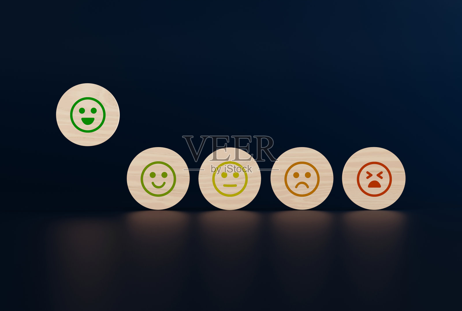 木制的圆盘上有从快乐到悲伤的面孔图标,一只手拿起一个有图标的圆盘。照片摄影图片