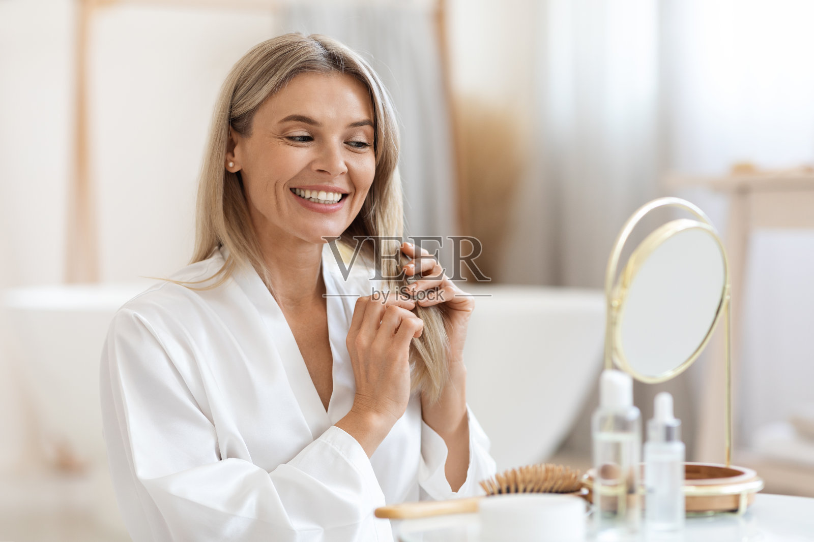 微笑的金发女人使用护发产品照片摄影图片