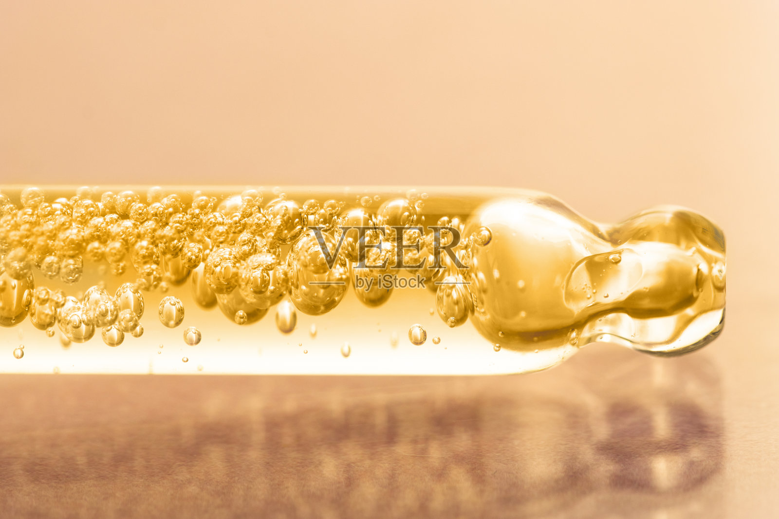 化妆品玻璃滴管与黄色精油,血清和大量的气泡前视图。一个带有液体产品的移液器的特写。照片摄影图片