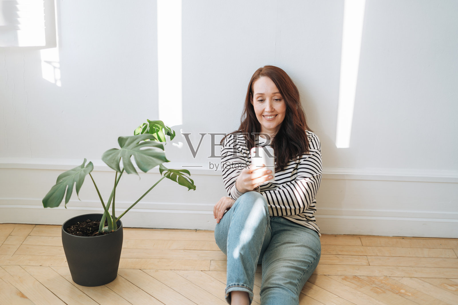 褐发微笑的女人在便装使用手机在家里照片摄影图片