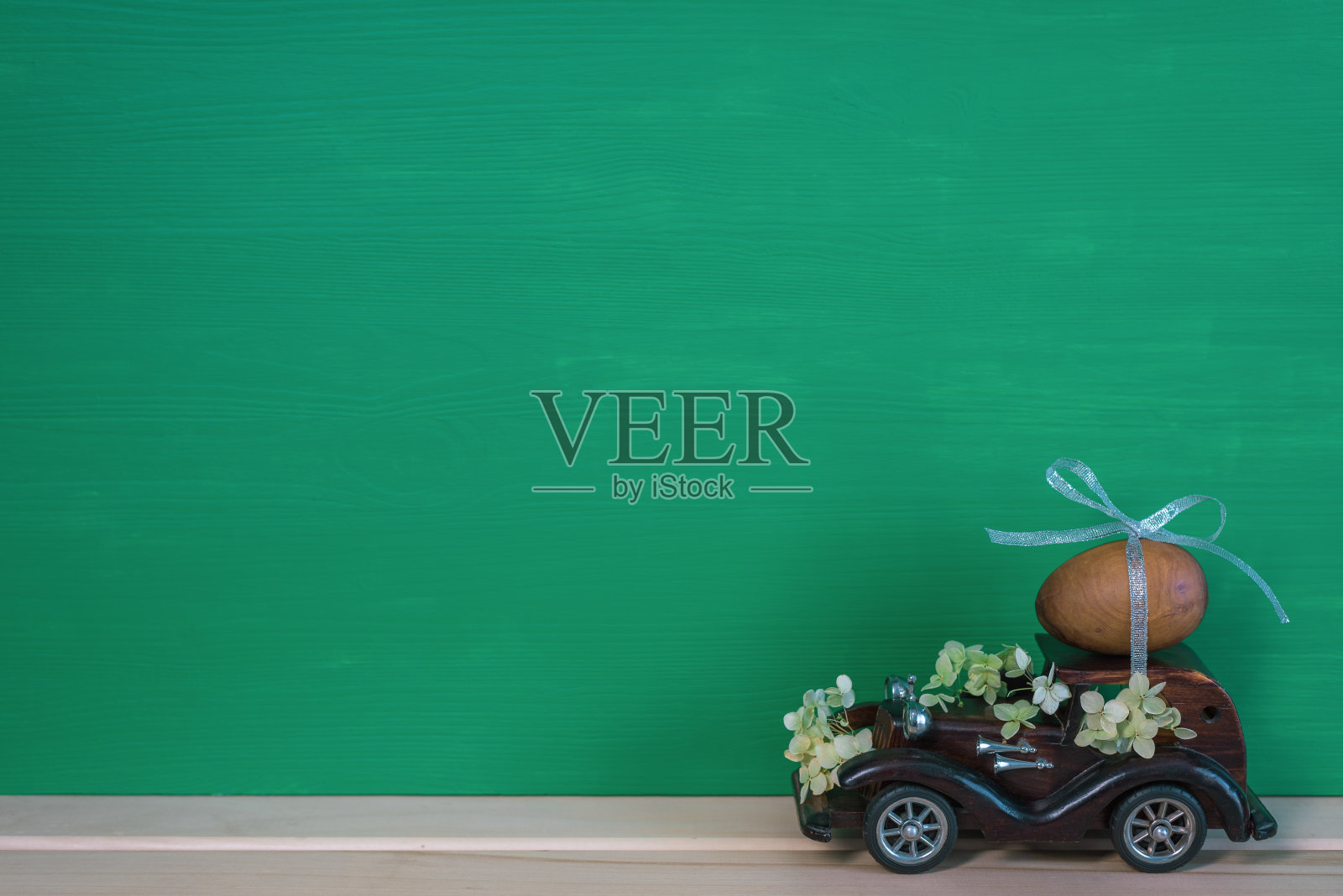 复活节假期。一辆棕色的木制玩具复古车载着一颗鸡蛋。复活节卡片和复古车照片摄影图片