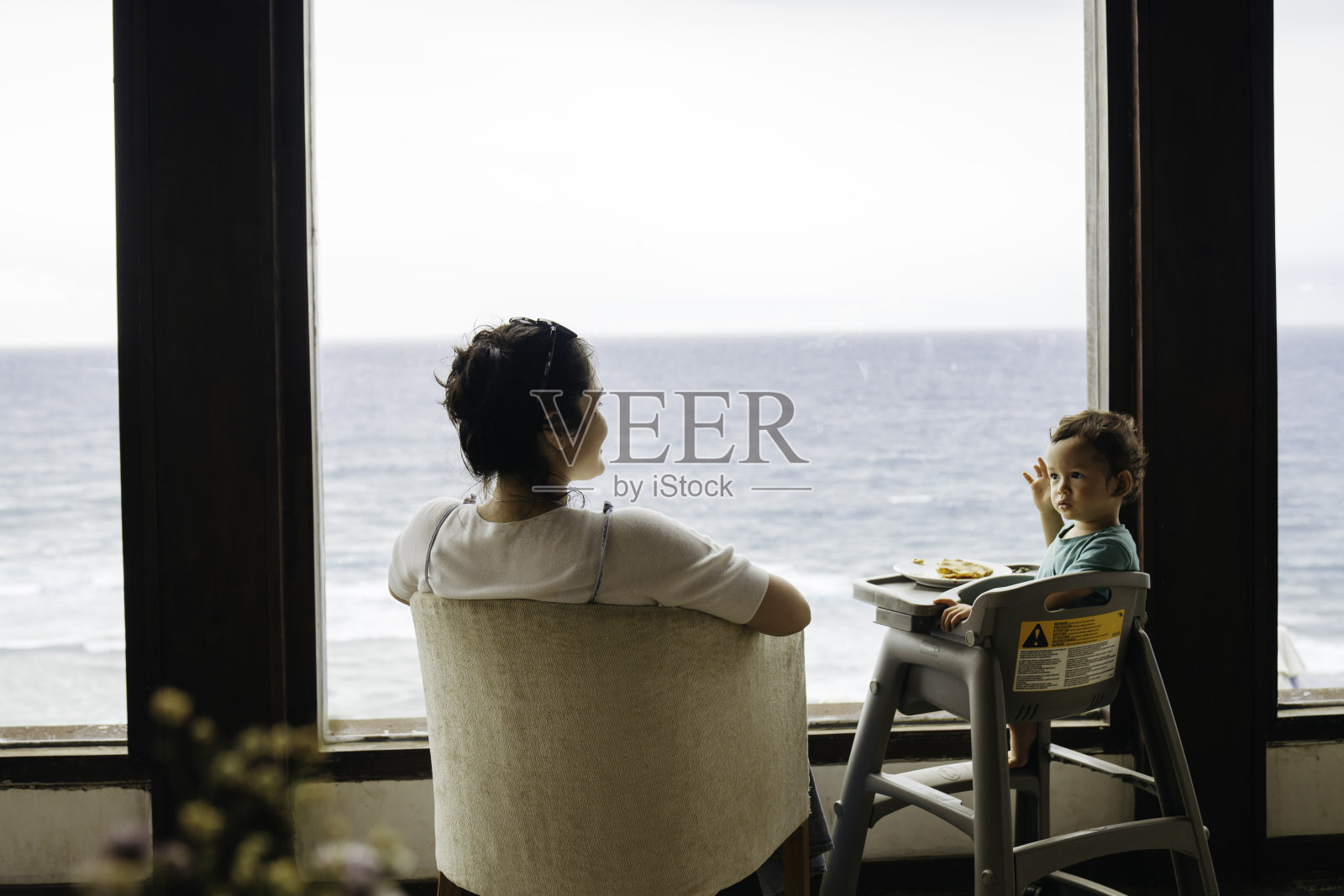 亚洲妇女和她的儿子坐在椅子上吃披萨照片摄影图片