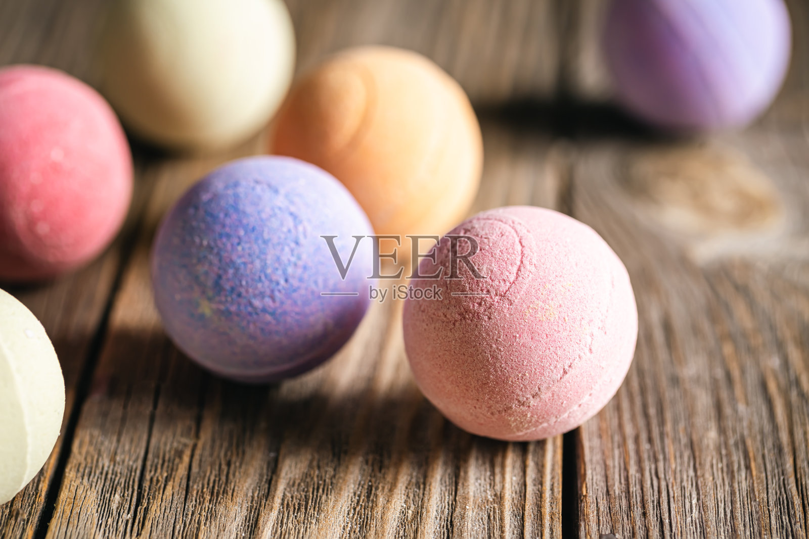 木质背景特写上的彩色浴弹。照片摄影图片