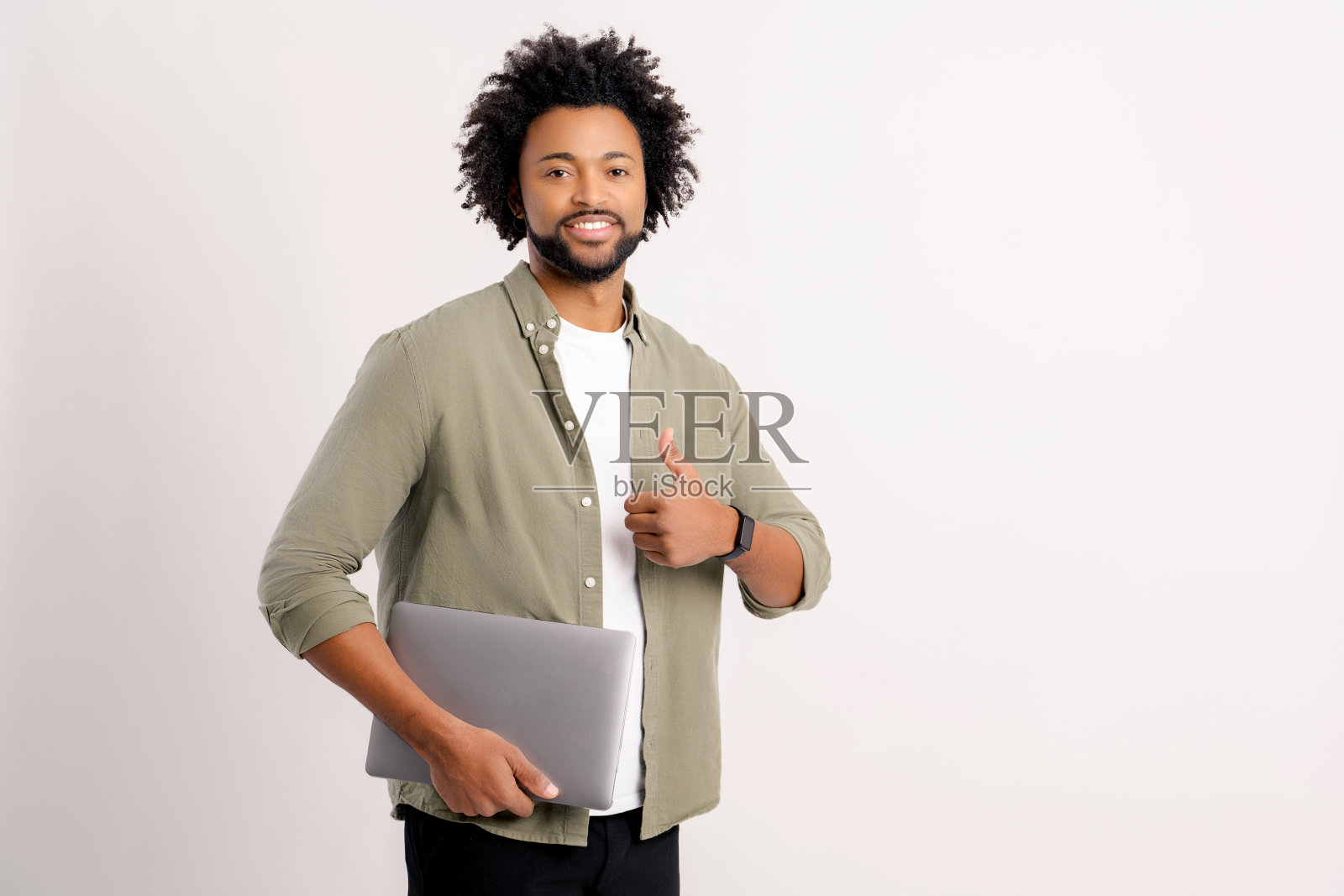 微笑卷曲的30岁男子在便装站与笔记本电脑隔离在白色,显示大拇指照片摄影图片