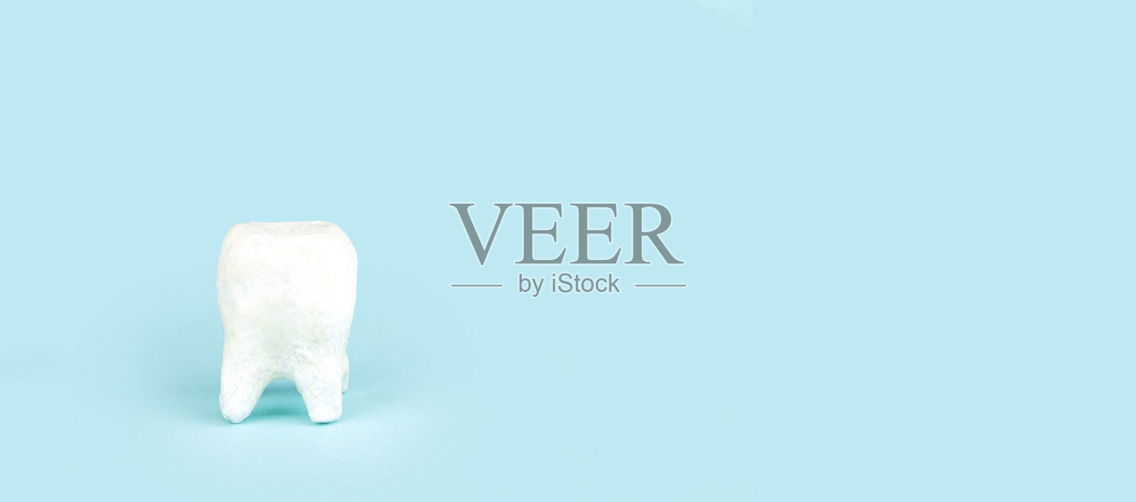 白色陶瓷牙齿在蓝色背景与复制空间,特写。照片摄影图片