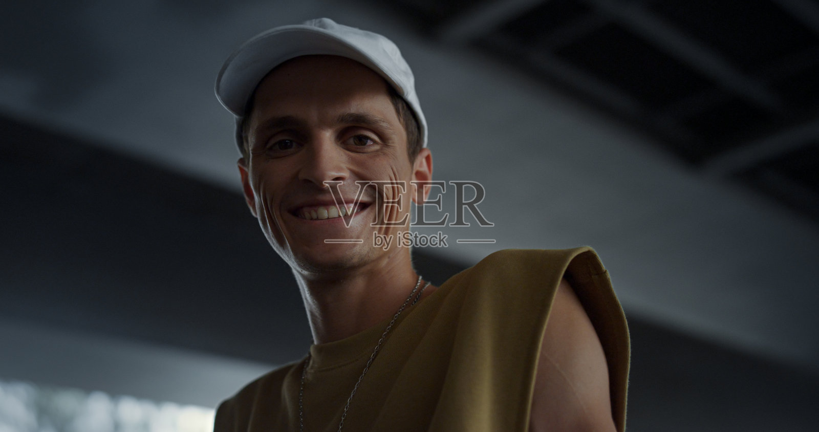 微笑的男子看着相机在滑板公园。漂亮男人的脸在户外。照片摄影图片