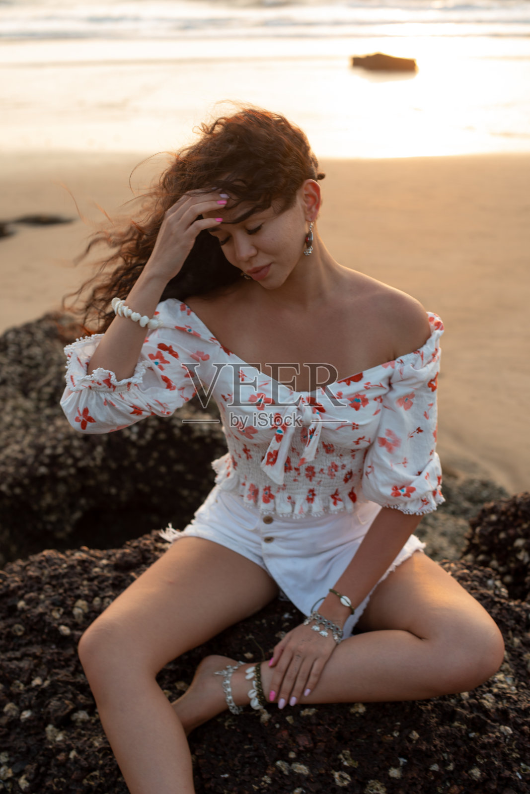 美丽的年轻女子坐在她的眼睛闭在海岸悬崖上日落的背景。享受的时刻。照片摄影图片