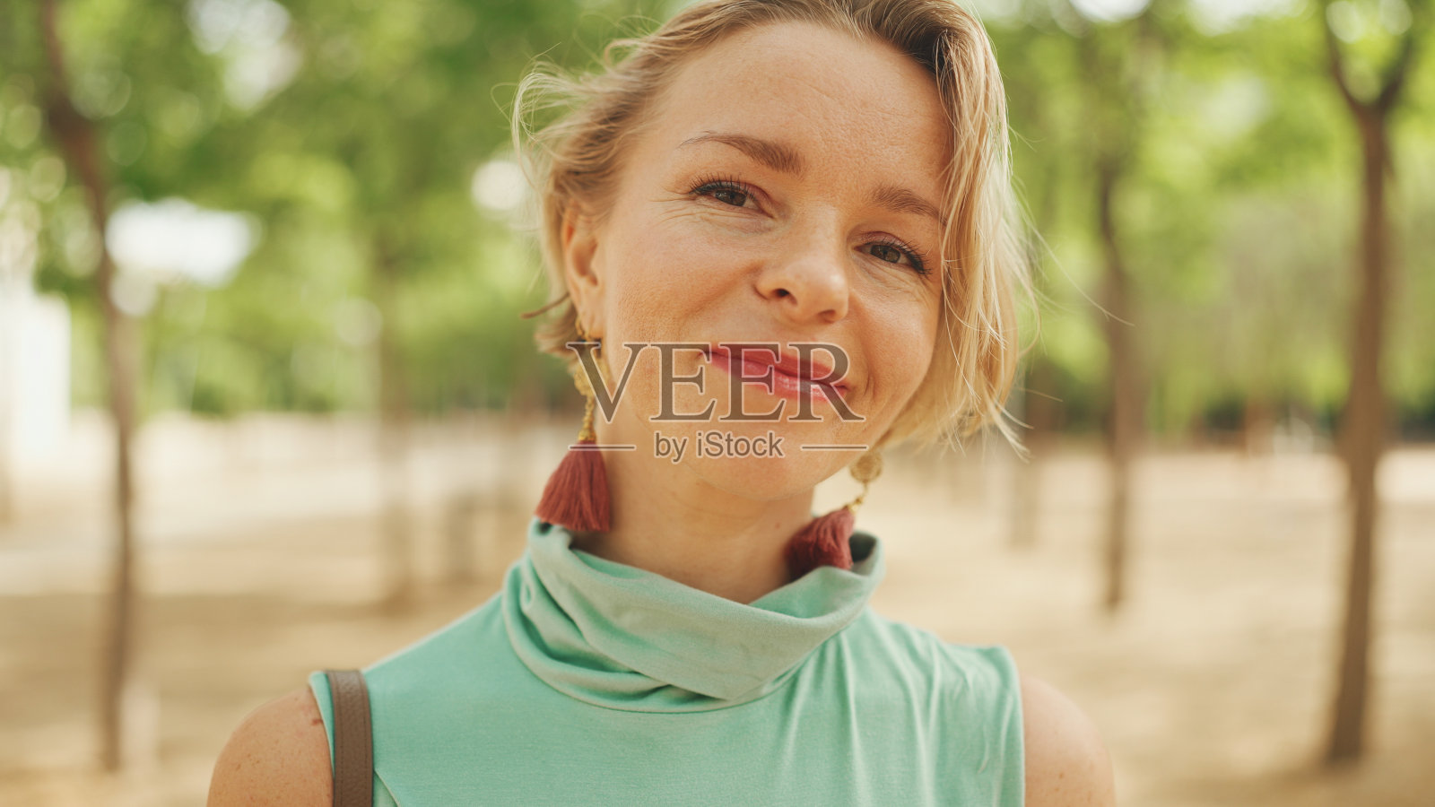 特写一个迷人的快乐的女人金发短发穿着休闲服,睁开眼睛,微笑着看着相机照片摄影图片