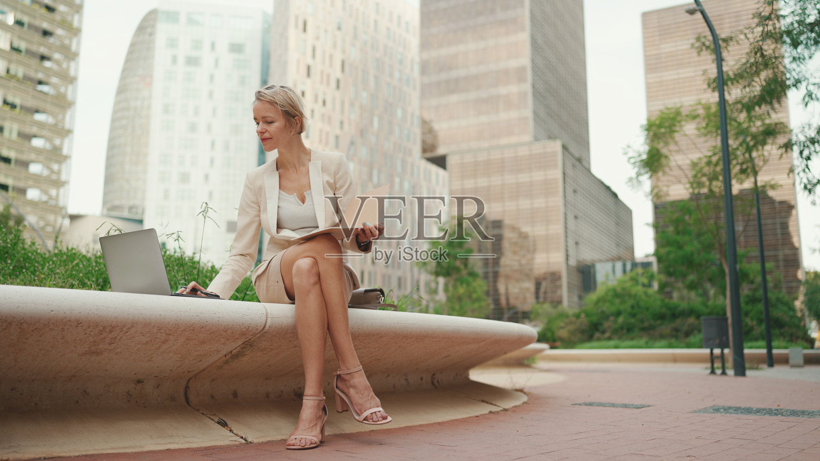 身穿米色西装的金发女商人使用pc笔记本电脑,写笔记照片摄影图片