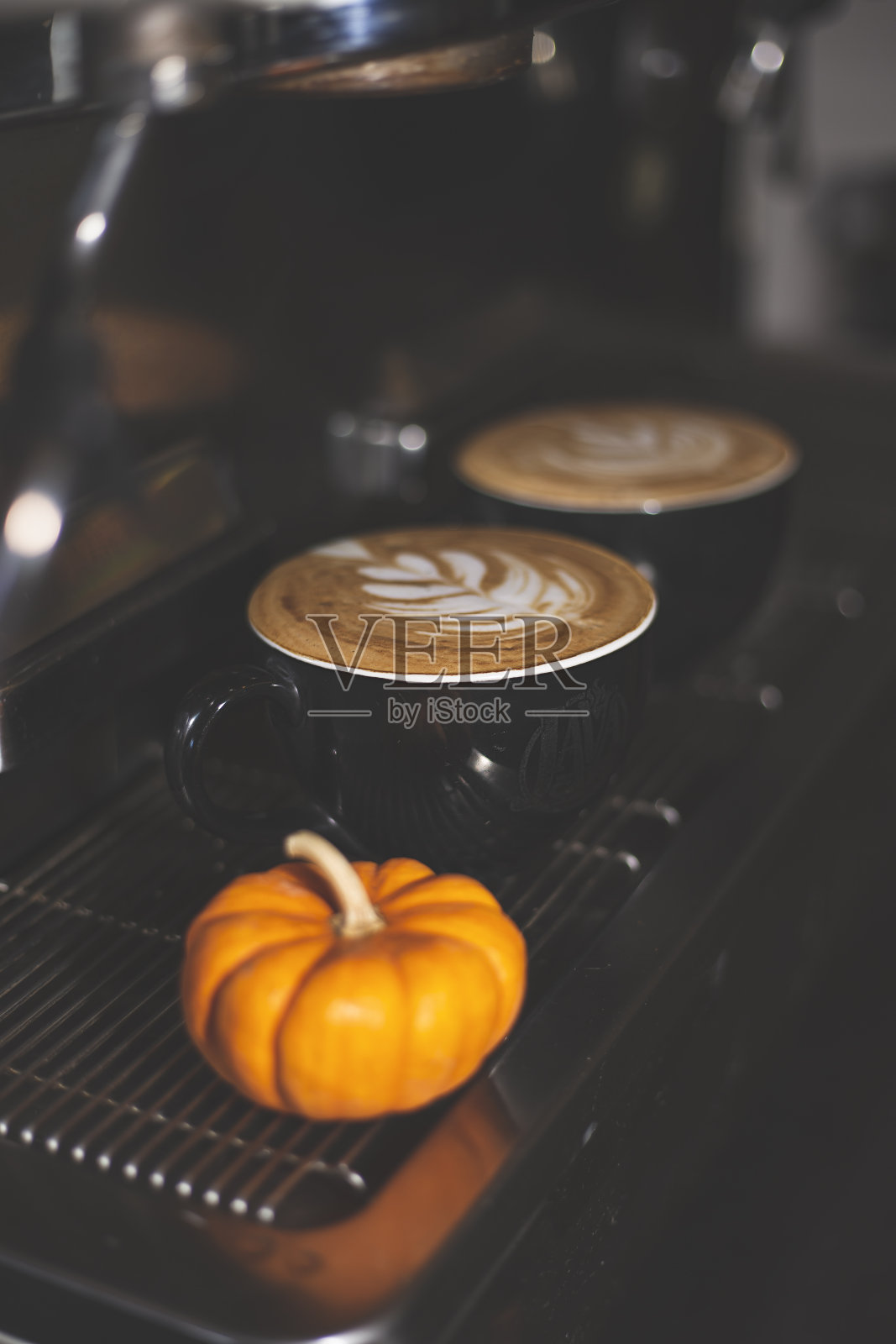 咖啡机里放着两杯现煮咖啡,旁边放着一个小南瓜。照片摄影图片