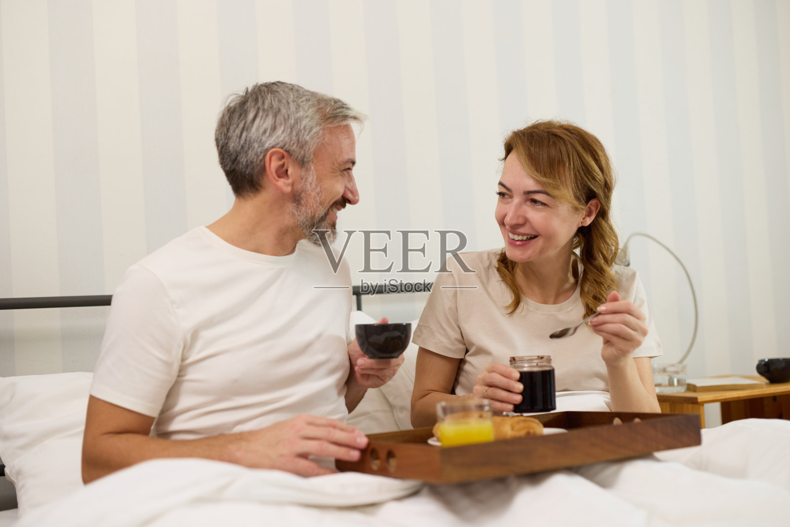 成熟的夫妇在床上享受咖啡和早餐照片摄影图片