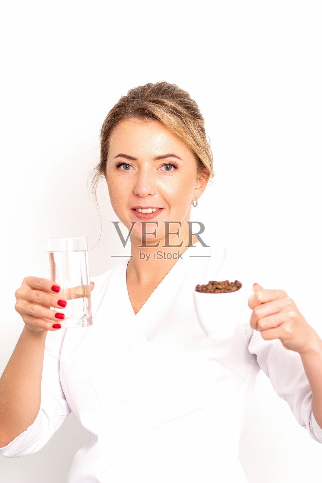 加水的咖啡。女营养师手里拿着一杯咖啡豆和一杯水,背景是白色的。照片摄影图片